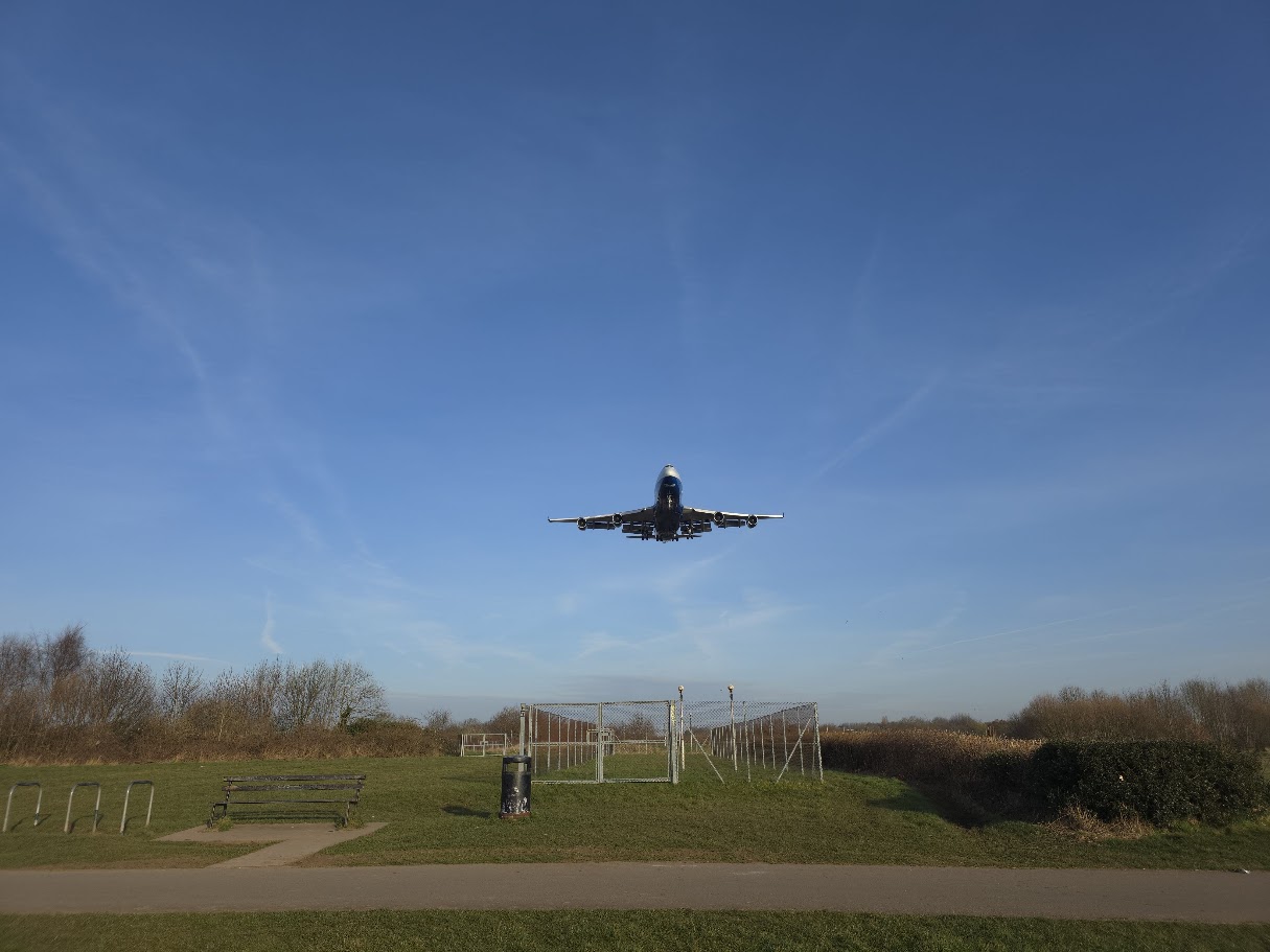 Wide-body aircraft on final approach directly over Sheldon — gear down, low and slow